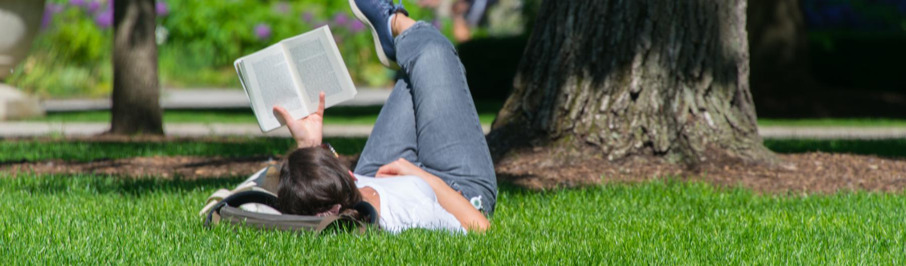 girl laying in the grass on the quad