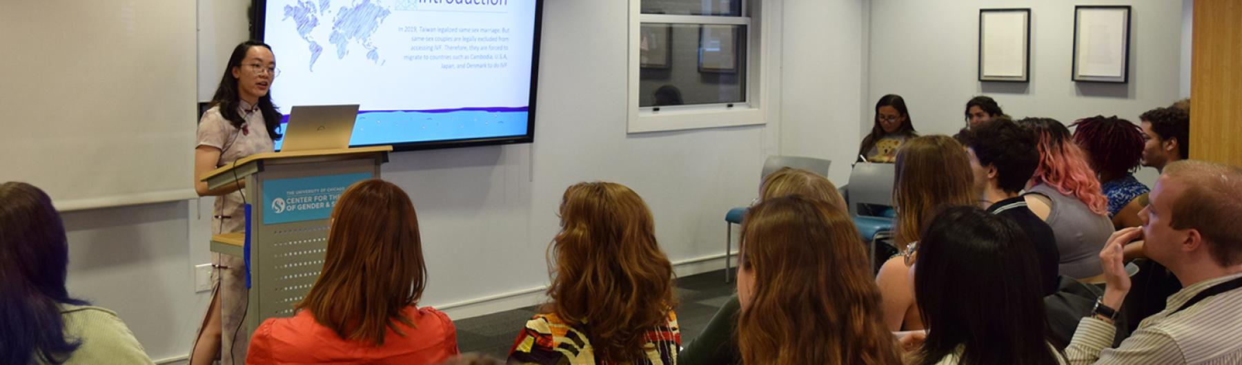 People seated listening to a speaker and looking at a presentation.